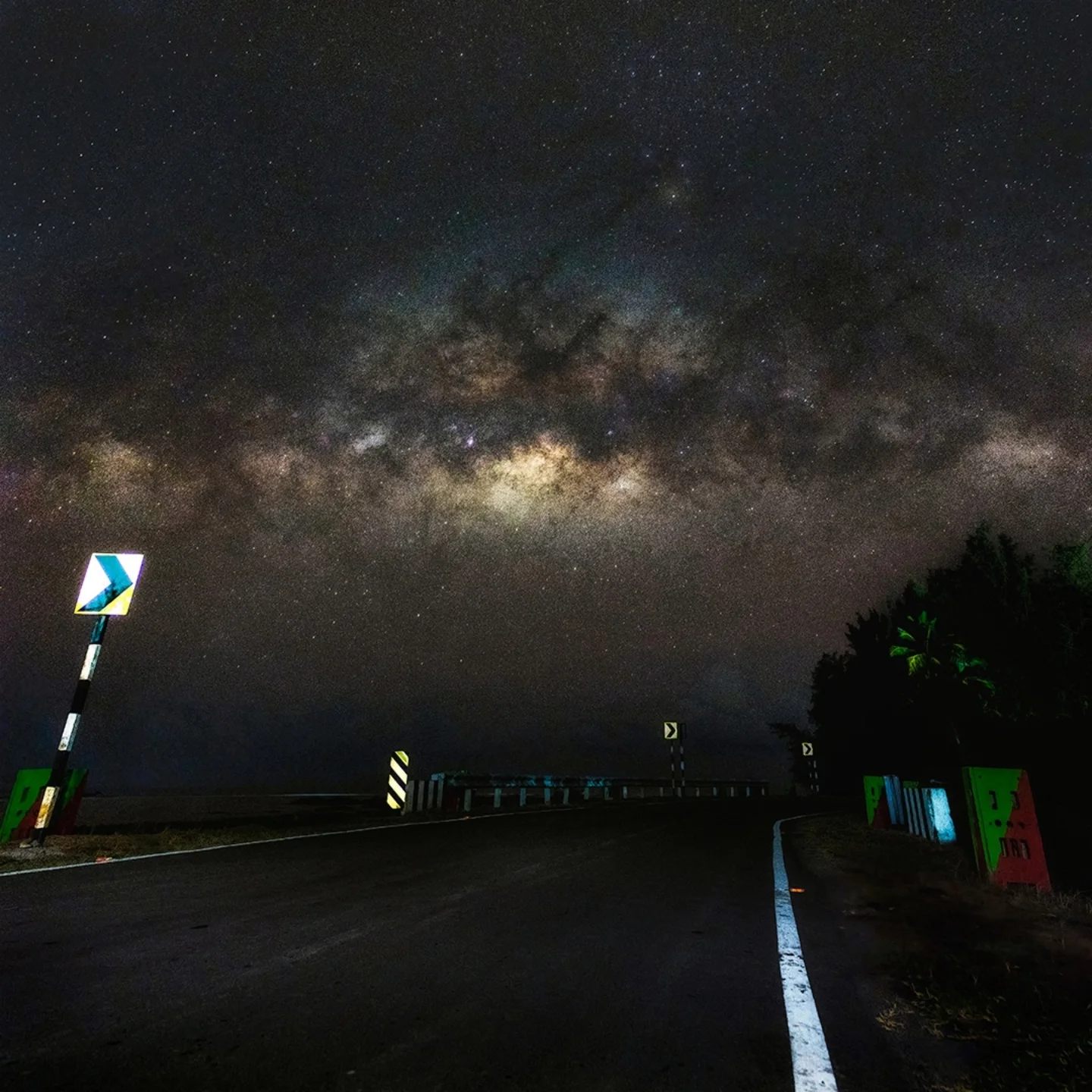 A night road lit by reflective markers under the Milky Way in the Andaman Islands.