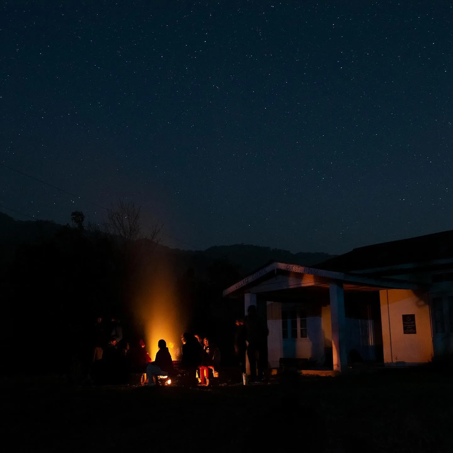 A campfire circle glowing under the stars outside a village guest house in Nagaland.