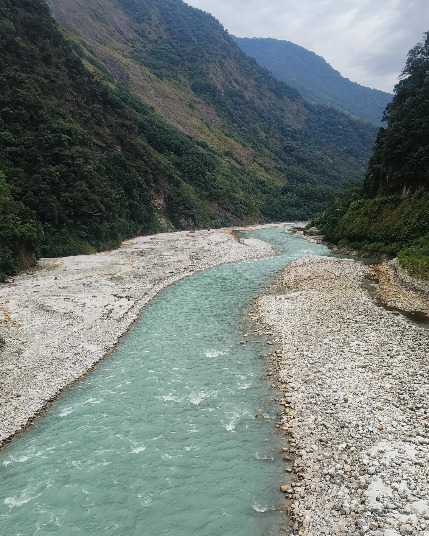 A turquoise glacial river cutting through a Himalayan gorge in Sikkim.