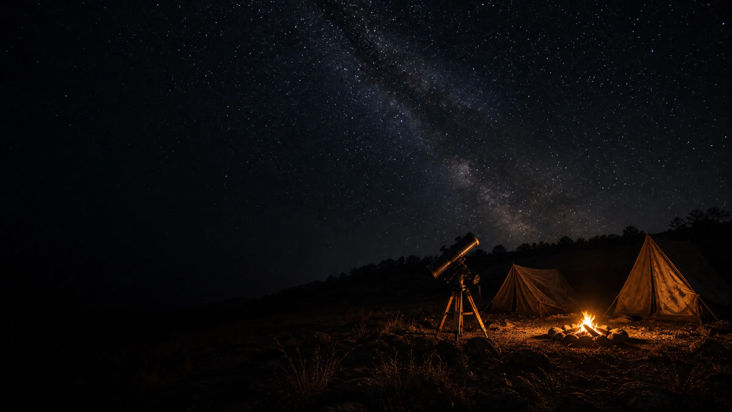 A telescope and two tents beside a campfire on a dark hillside, the Milky Way visible overhead.